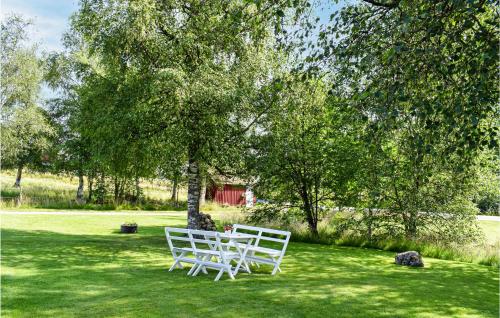 two white chairs sitting in the grass under a tree at 2 Bedroom Nice Home In Smålandsstenar in Åtterås