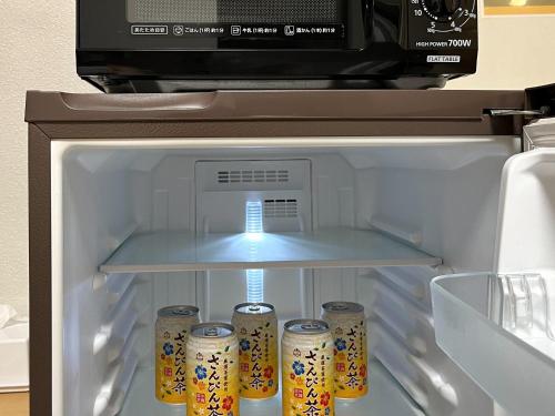 an open refrigerator with soda cans in it at Across Omoromachi Naha in Naha