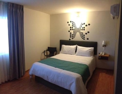 een slaapkamer met een bed en een lampje aan de muur bij Hotel Dajana Boulevard in León