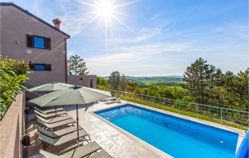 an outdoor swimming pool with an umbrella and a house at Amazing Home In Gracisce With Sauna in Gračišče