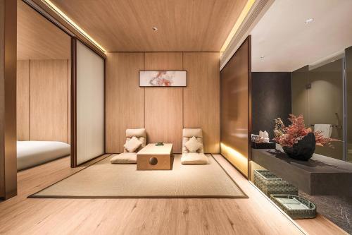 a room with a bed and two chairs and a table at Howard Johnson Royal Hotel Shenzhen in Bao'an
