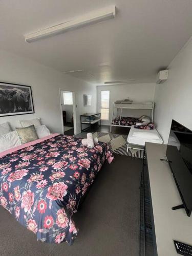 a bedroom with a bed with a floral bedspread at T Two Salty Shack - right across from the beach! in Papamoa