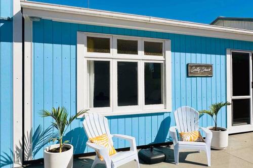 two chairs sitting in front of a blue building at T Two Salty Shack - right across from the beach! in Papamoa