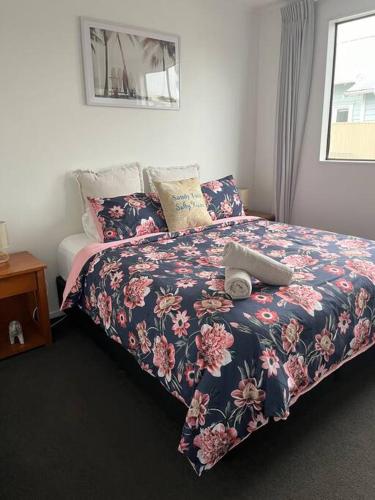 a bedroom with a bed with a floral comforter at T Two Salty Shack - right across from the beach! in Papamoa