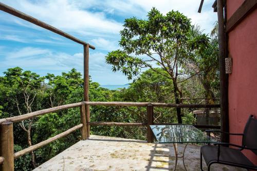 a balcony with a glass table and chairs and trees at Pousada Encanto das Águas in Ilhabela