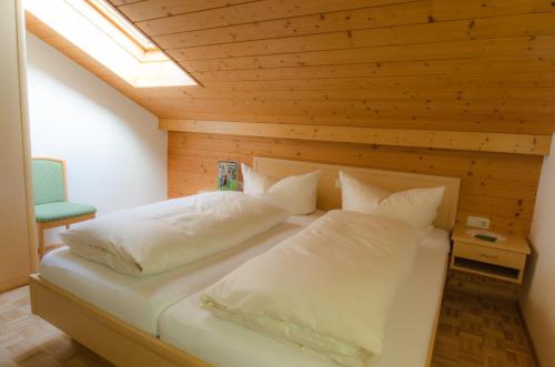 Schlafzimmer mit einem Bett mit Holzdecke in der Unterkunft Ferienbauernhof Roth in Sulzberg