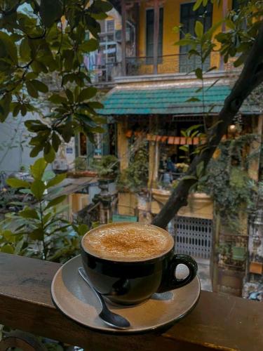 a cup of coffee sitting on a table with a spoon at Hanoi Win Hotel & Travel in Hanoi