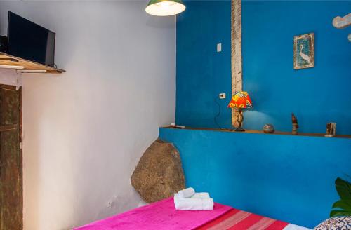 a bedroom with a blue wall and a bed with a pink sheet at Pousada Encanto das Águas in Ilhabela