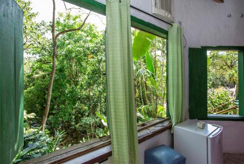 a bathroom with a window and a toilet and trees at Pousada Encanto das Águas in Ilhabela