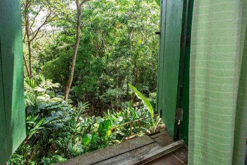 an open door to a garden with trees and plants at Pousada Encanto das Águas in Ilhabela