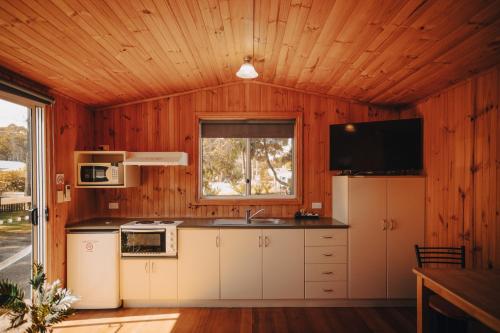a kitchen with a refrigerator and a sink and a window at Strahan Beach Tourist Park in Strahan