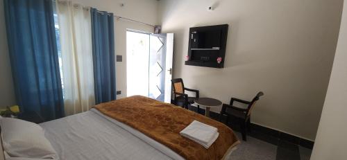 a bedroom with a bed and a table with chairs at Hotel HBH Himalaya's Beautiful Hills in Uttarkāshi