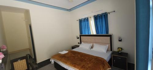 a bedroom with a large bed with blue curtains at Hotel HBH Himalaya's Beautiful Hills in Uttarkāshi