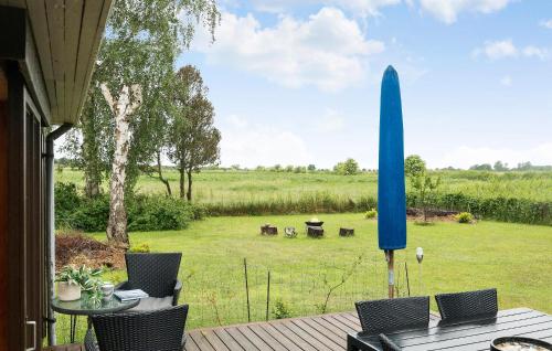 a patio with a table and chairs and a blue umbrella at Amazing Home In Stege With Kitchen in Stege