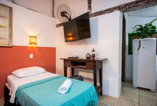 a bedroom with a bed and a desk and a tv at Pousada Encanto das Águas in Ilhabela