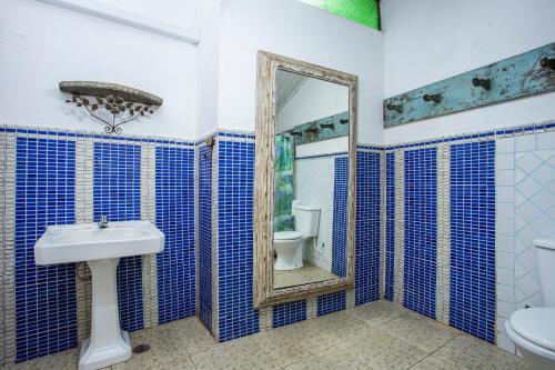 a blue tiled bathroom with a toilet and a mirror at Pousada Encanto das Águas in Ilhabela