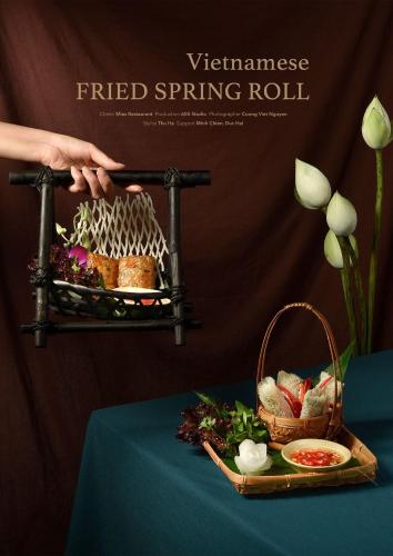 a person holding a bird cage on a table with a plate of food at Hanoi Win Hotel & Travel in Hanoi