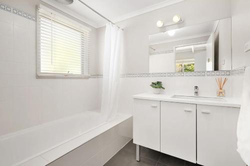 a white bathroom with a white tub and a sink at Willowdene pool spa tennis court in Rye