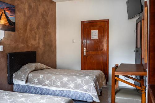 a bedroom with two beds and a wooden door at Hotel María de la Luz in Valladolid