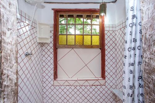 a bathroom with a window and a shower curtain at Pousada Encanto das Águas in Ilhabela