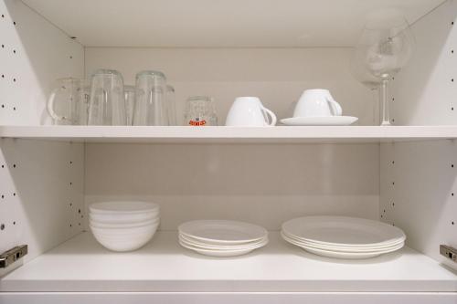 a white pantry with plates and bowls on shelves at The Title Residencies Nai Yang - 1 Bedroom Apartment in Nai Yang Beach