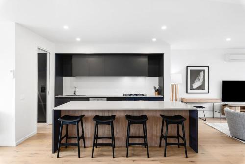 a kitchen with a large island with four bar stools at Anchorage Villa - Chic, Pet Friendly by Marina in Safety Beach