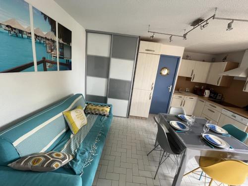 un salon avec un canapé bleu et une table dans l'établissement Gruissan: T3, 4 Pers, Piscine, Parking, Proche Commerce, Environnement Calme, Accès Plage - FR-1-796-14, à Gruissan