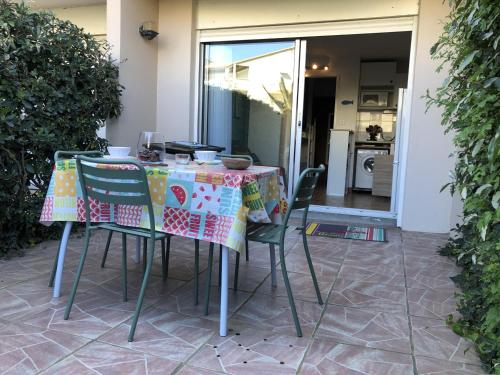une table avec des chaises et un chiffon de table dans l'établissement Studio Alcôve en Front de Mer avec Piscine, Terrasse et Parking à Saint Cyprien - FR-1-793-14, à Saint-Cyprien