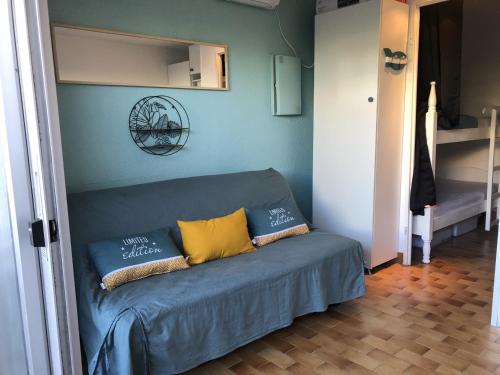 un canapé bleu avec deux oreillers dessus dans une pièce dans l'établissement Studio Alcôve en Front de Mer avec Piscine, Terrasse et Parking à Saint Cyprien - FR-1-793-14, à Saint-Cyprien