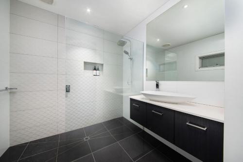 Un baño blanco con lavabo y espejo. en Missy's Escape - Luxe Family Entertainer Pool Spa Walk to Beach, en Mornington