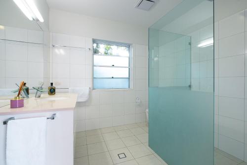 a bathroom with a glass shower and a sink at Tallows House on Paterson in Byron Bay