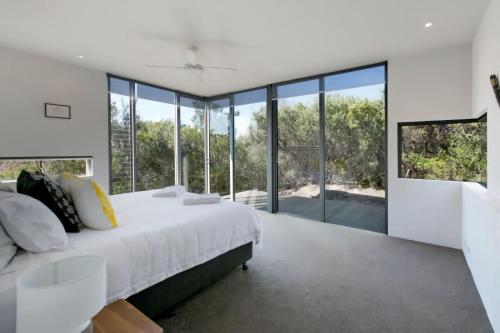 Un dormitorio con una cama grande y grandes ventanales. en Oceania Retreat - Private beach access pool OFP, en Rye