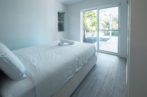 a bedroom with a white bed and a sliding glass door at Tallows House on Paterson in Byron Bay