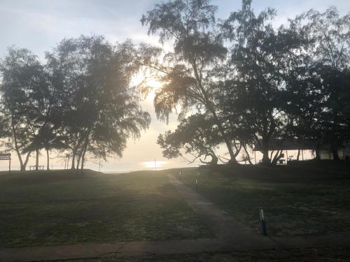 a field with trees with the sun setting in the background at Samsuria Beach Apartment Resort in Kuantan