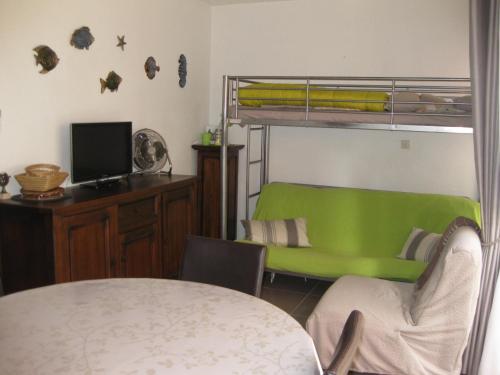 - une chambre avec des lits superposés et un canapé vert dans l'établissement Saint Cyprien - Agréable T2 Climatisé, Parking Privé, Balcon & Solarium, 300m Plage - FR-1-793-12, à Saint-Cyprien