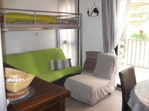 un salon avec un lit superposé vert et une chaise dans l'établissement Saint Cyprien - Agréable T2 Climatisé, Parking Privé, Balcon & Solarium, 300m Plage - FR-1-793-12, à Saint-Cyprien