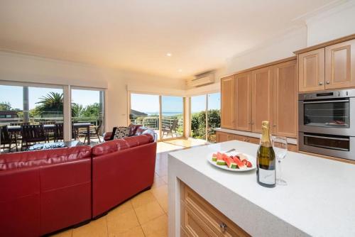 a kitchen with a red couch and a bowl of fruit on a counter at Vue de la Mer Luxe Retreat - Tennis, Pool, Views in Mount Martha