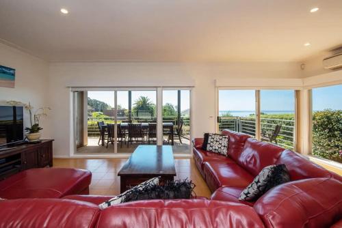 a living room with a red couch and a table at Vue de la Mer Luxe Retreat - Tennis, Pool, Views in Mount Martha