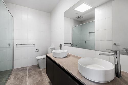 ein weißes Badezimmer mit zwei Waschbecken und einer Toilette in der Unterkunft Castaway Villa - Luxe on the Marina Walk to Beach in Safety Beach
