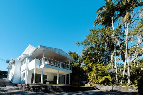 a white house with palm trees in front of it at Tallows House on Paterson in Byron Bay