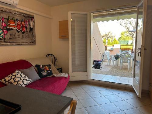 un salon avec un canapé et une porte coulissante en verre dans l'établissement Joli T2 Climatisé avec Cour Privée et Parking, à 500m Plage et Port - Saint Cyprien - FR-1-793-2, à Saint-Cyprien