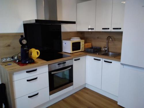 une cuisine avec des armoires blanches et un micro-ondes dans l'établissement Gruissan - T2 Mezzanine Climatisé Proche Plage - 5/6 Pers - Parking Privé - Tout Équipé - FR-1-796-23, à Gruissan