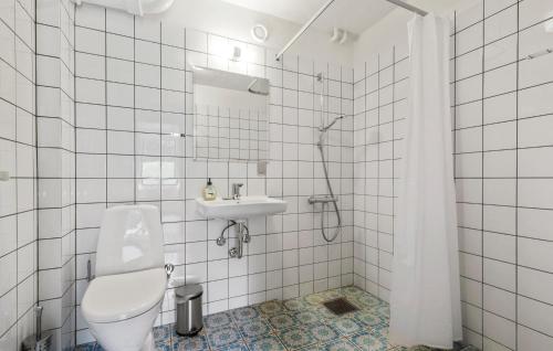 a white tiled bathroom with a toilet and a sink at Gorgeous Home In Glesborg in Glesborg