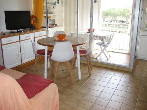 une cuisine avec une table et des chaises et une télévision dans l'établissement Saint Cyprien T2 Mezzanine 4P avec Parking, Belle vue Lagune et Mer - FR-1-793-11, à Saint-Cyprien