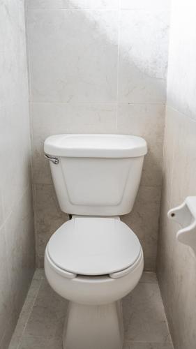 a white toilet in a bathroom with a toilet paper dispenser at Hotel María de la Luz in Valladolid