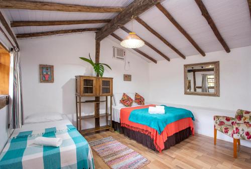 a room with two beds and a chair in it at Pousada Encanto das Águas in Ilhabela