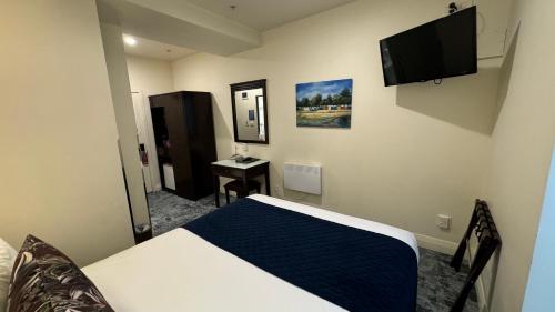 a bedroom with a bed and a television on the wall at Trinity Hotel in Wellington