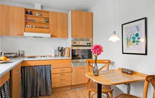 a kitchen with wooden cabinets and a table with a vase of flowers at One-Bedroom Holiday Home In Ribe in Ribe
