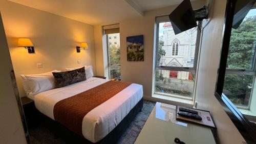 a hotel room with a bed and two windows at Trinity Hotel in Wellington