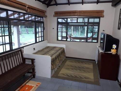 a bedroom with a bed and a tv and windows at Recanto das Saíras in Morretes